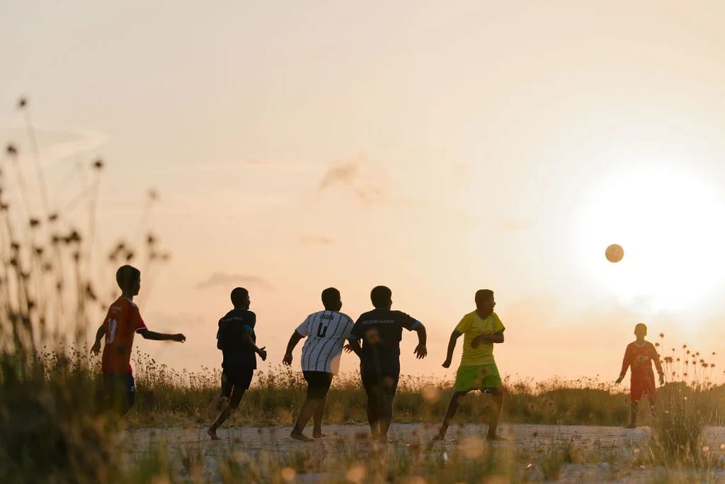 Children playing football in the warm light of sunset