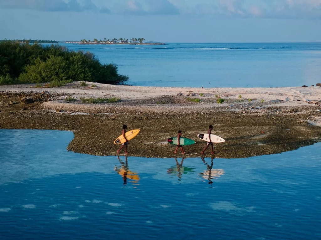 Surfers and their boards reflected in still water beside the reef