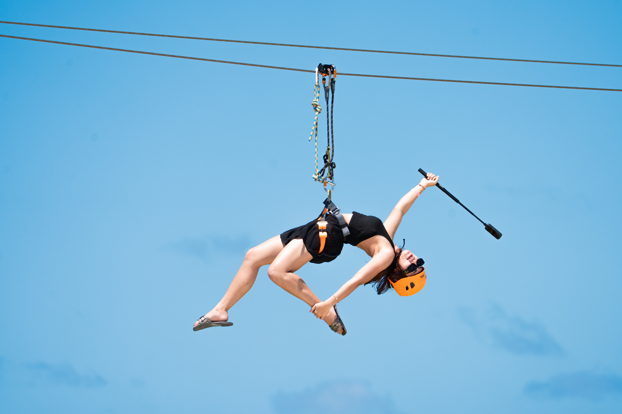 A rider gliding on Zipline Maldives against a clear blue sky
