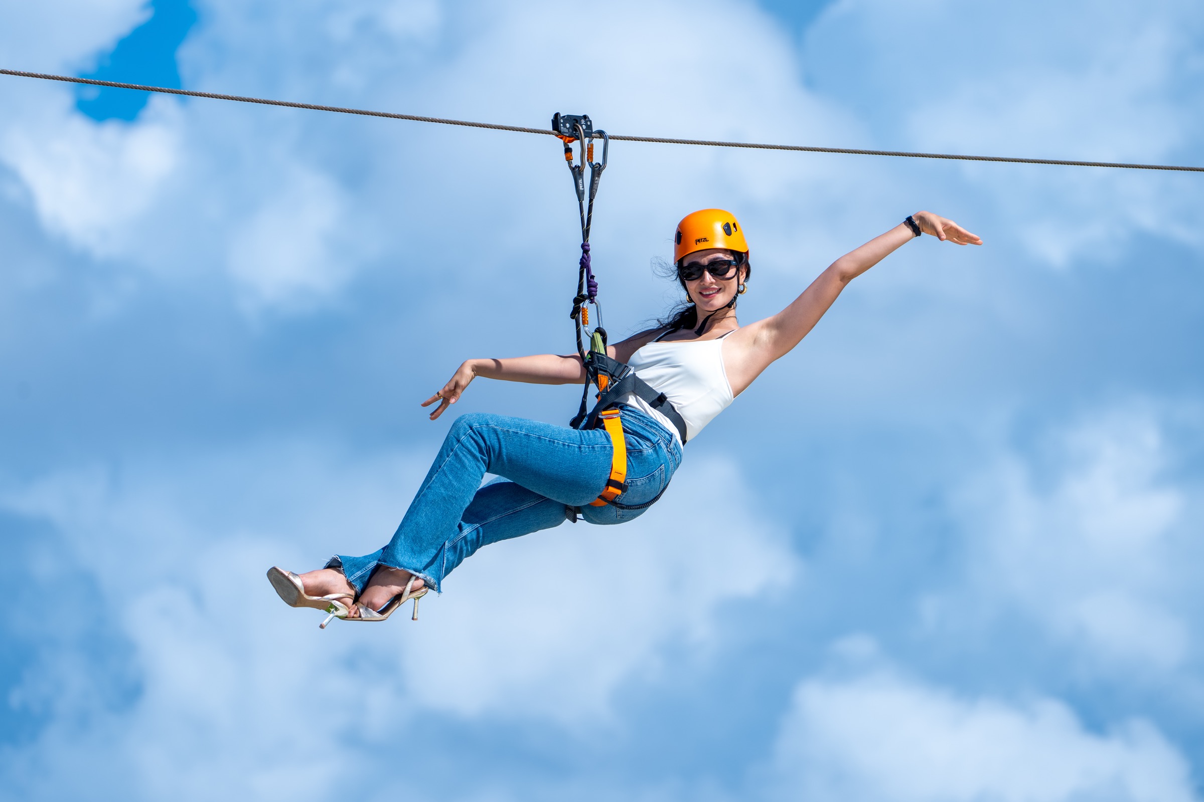 A Zipline Maldives rider smiling against a cloud-filled blue sky